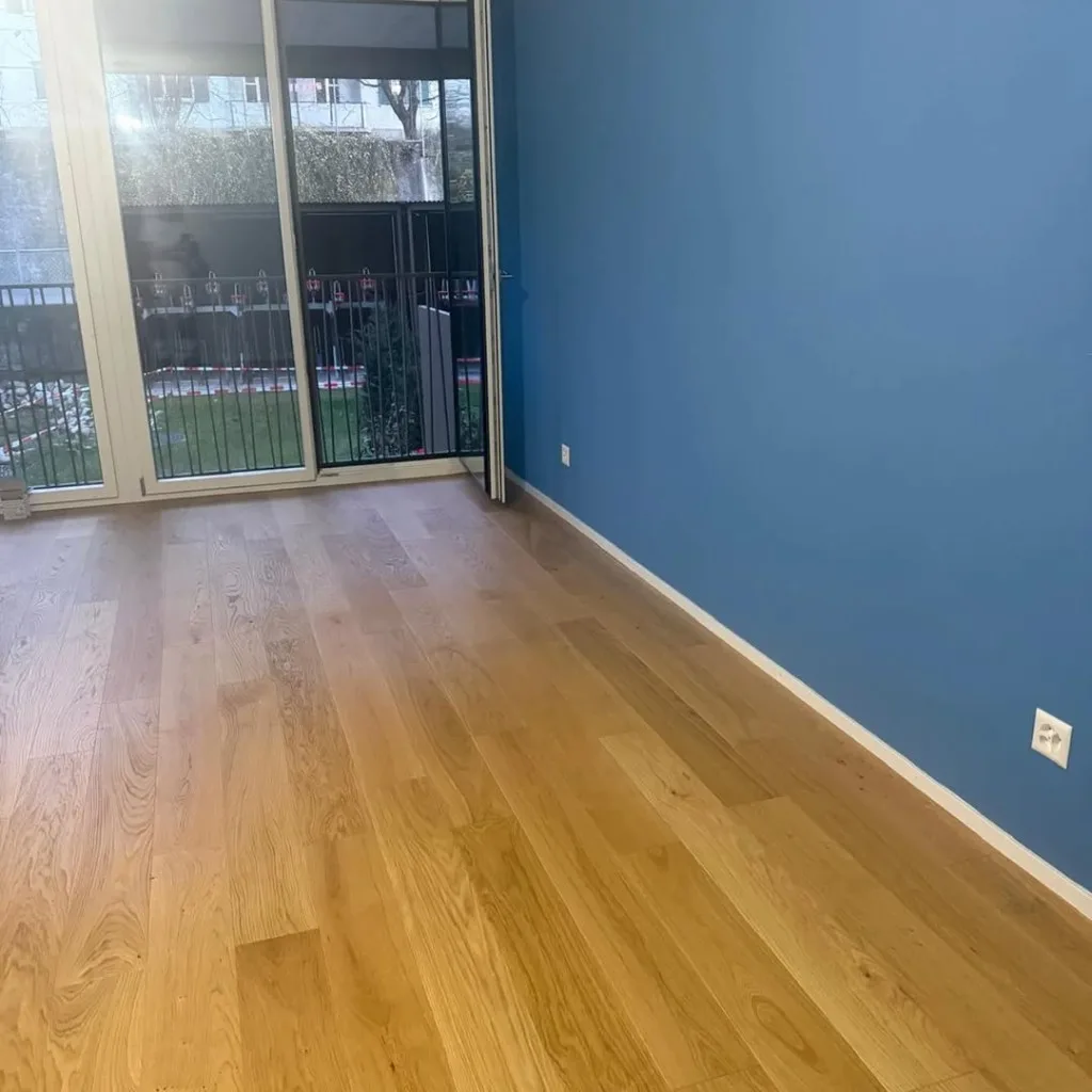 Innenanstrich einer Wohnung, Wohnraum mit blauer Akzentwand, weißen Wänden und Eichenparkett